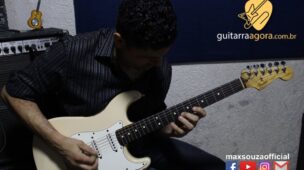 homem sentado tocando guitarra branca